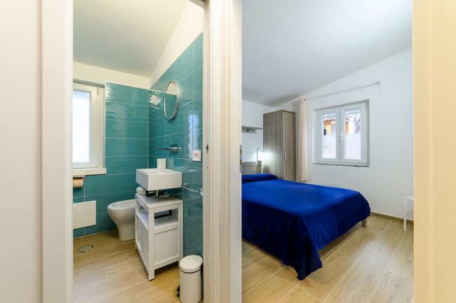 Bagno e camera con pareti bianche e blu.