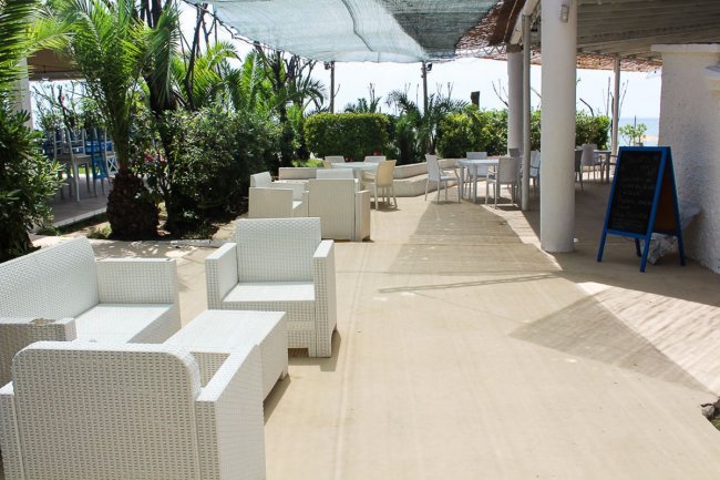 Sedie bianche all'aperto in un caffè soleggiato.