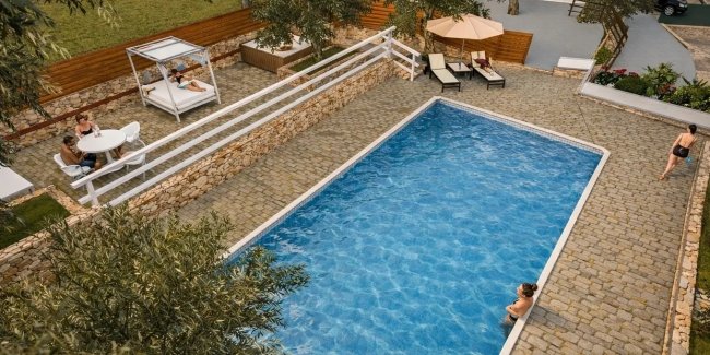 Piscina circondata da sdraio e ombrelloni.