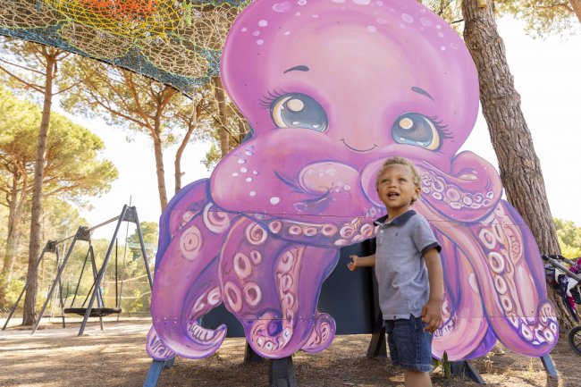 Bambino accanto a un cartonato di polpo viola sorridente.