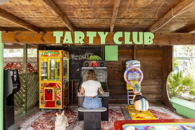 Sala giochi con persona seduta e giochi arcade.