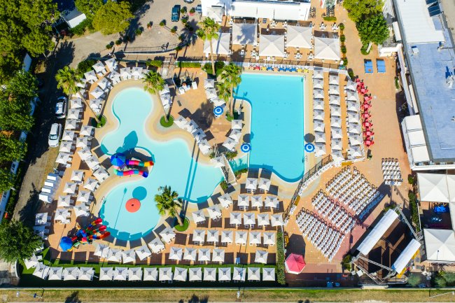 Vista aerea di piscine e lettini con ombrelloni.