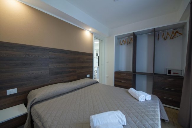 Camera da letto con letto matrimoniale e armadio aperto.