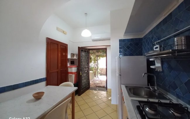 Cucina con tavolo bianco, fornelli e pareti piastrellate blu.