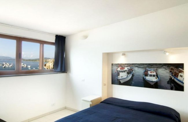 Camera da letto con vista mare e foto di barche.