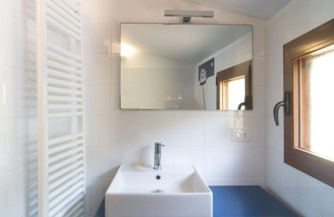 Bagno moderno con specchio grande e lavabo bianco.