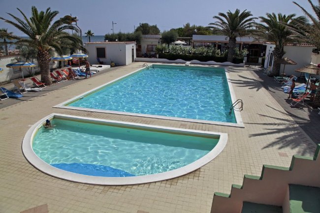 Piscina con palme e sdraio.