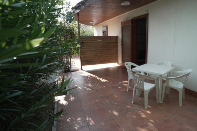 Patio esterno con tavolo e sedie, piante.