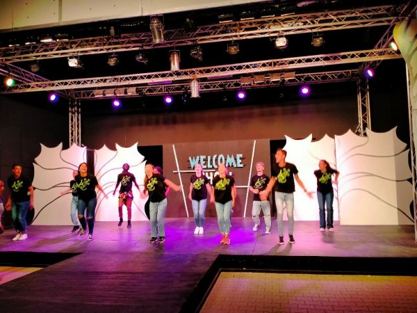 Persone che ballano su un palco con scritta 