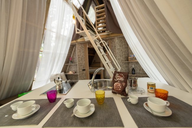 Angolo cottura con stoviglie colorate e scala a chiocciola.