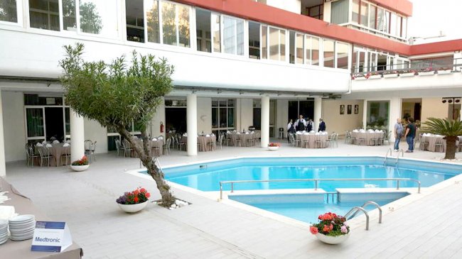 Piscina circondata da tavoli apparecchiati e un edificio con finestre.