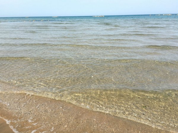 Mare con onde leggere che arrivano sulla spiaggia sabbiosa.