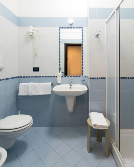 Un bagno con piastrelle blu, lavandino, doccia e WC.