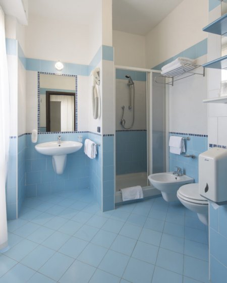 Un bagno con piastrelle blu, lavabo, doccia, WC e bidè.