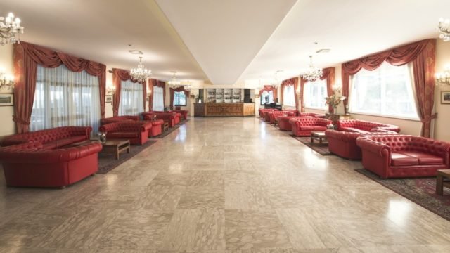 Ampio salone con divani rossi e grandi finestre.