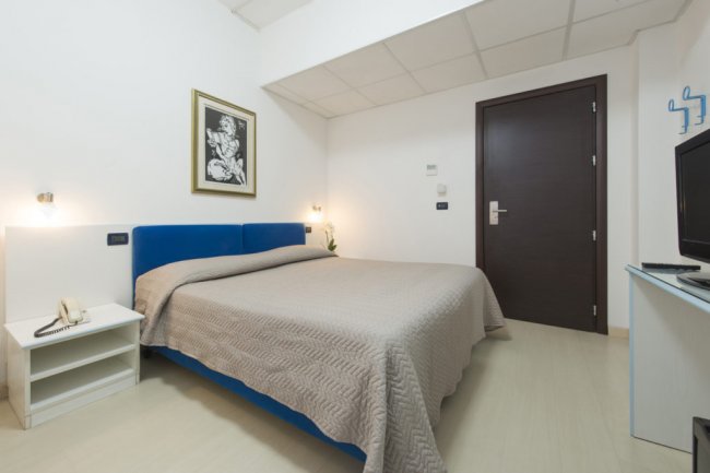 Camera moderna con letto matrimoniale e pareti bianche.