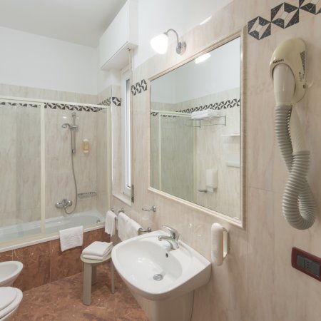Bagno con vasca, lavabo, specchio e asciugacapelli a parete.
