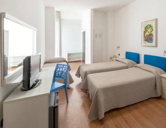 Una camera con tre letti singoli e TV.