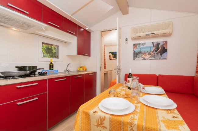 Cucina rossa con tavolo apparecchiato e divano arancione.