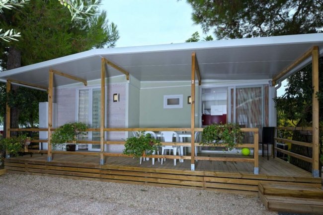 Bungalow con veranda in legno e piante appese.