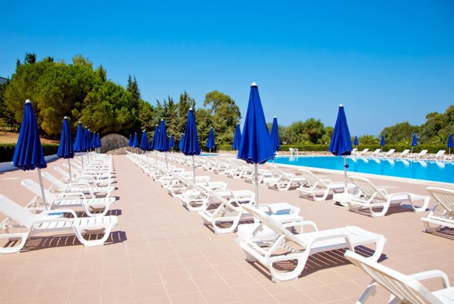 File di lettini bianchi e ombrelloni blu.