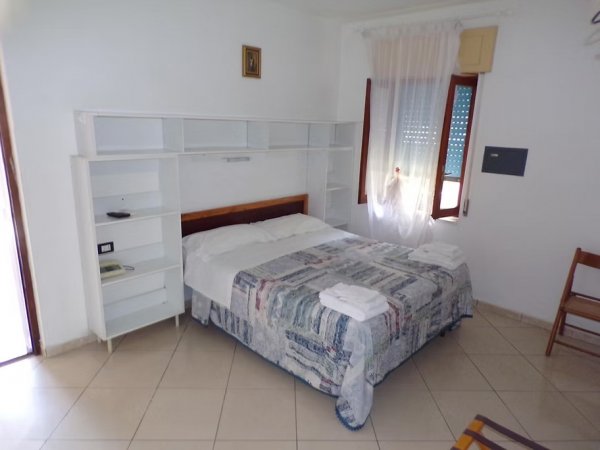 Letto matrimoniale in una stanza luminosa con scaffali.