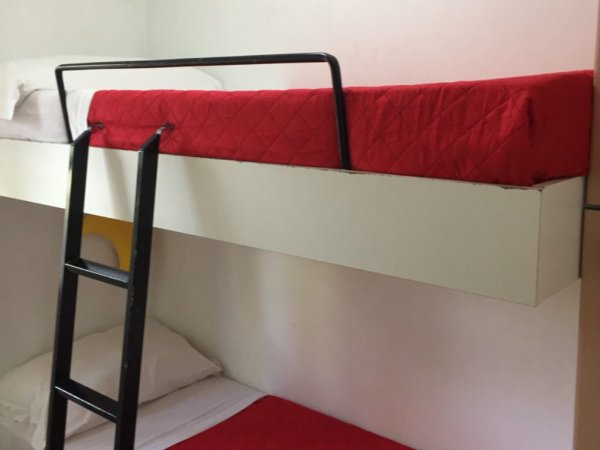 Letto a castello con lenzuola rosse.