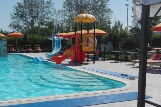 Piscina con scivoli per bambini e ombrelloni.