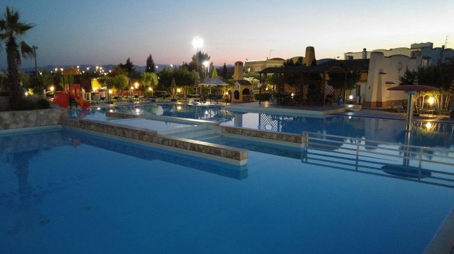 Piscina grande al tramonto con luci.