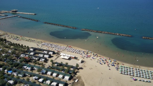 Spiaggia con ombrelloni colorati e mare calmo.