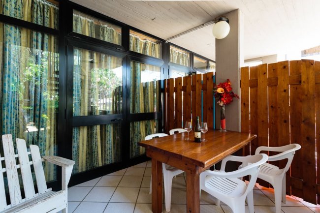 Area esterna con tavolo in legno e sedie.