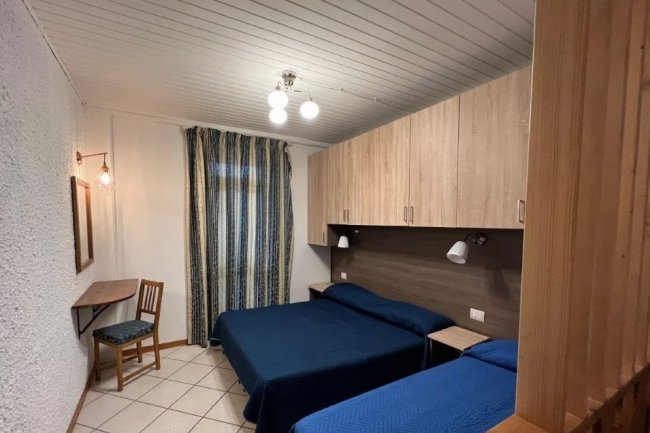 Camera con due letti, scrivania e armadio.