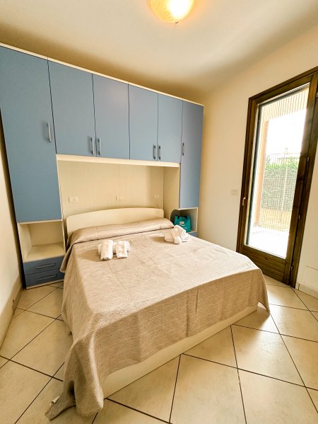 Camera da letto con armadio azzurro e porta finestra.