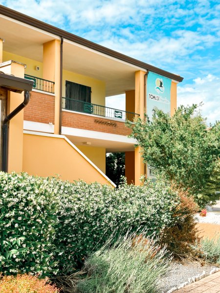 Edificio giallo con balcone e vegetazione.