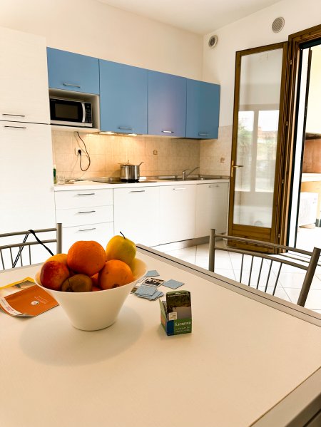 Cucina con pensili blu e tavolo con frutta.