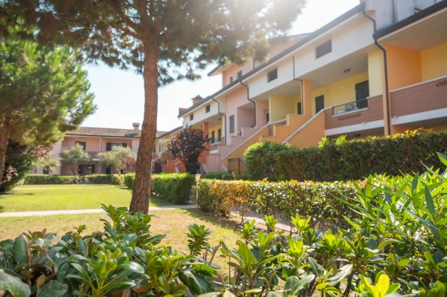 Giardino con edificio residenziale e alberi.