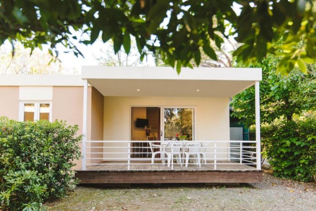 Veranda con sedie bianche davanti a una casa moderna.