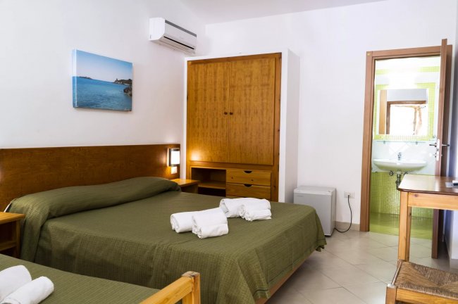 Camera con letto matrimoniale, armadio in legno e bagno annesso.