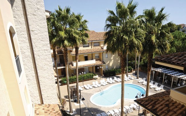 Piscina circondata da palme e lettini.