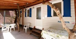 Casa mobile con patio coperto e sedie verdi.
