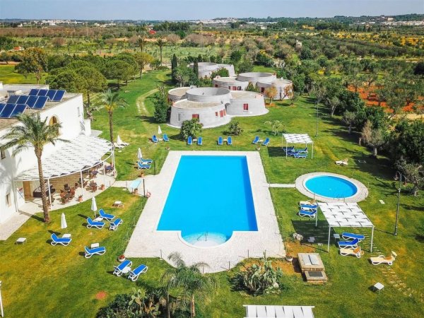 Una piscina all'aperto con lettini e giardino circostante.