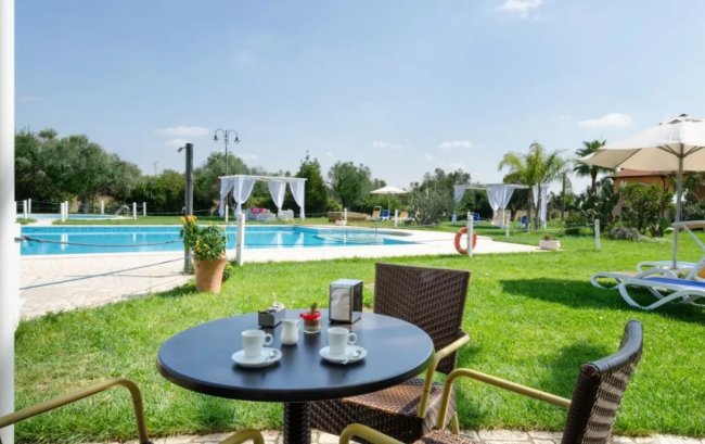 Tavolino con caffè vicino a una piscina in un giardino verde.