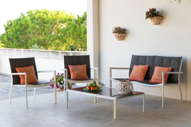 Set da esterno con divani, tavolino e cuscini arancioni su una terrazza.