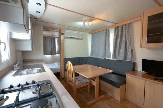 Interno di una casa mobile con cucina, tavolo da pranzo e area salotto.