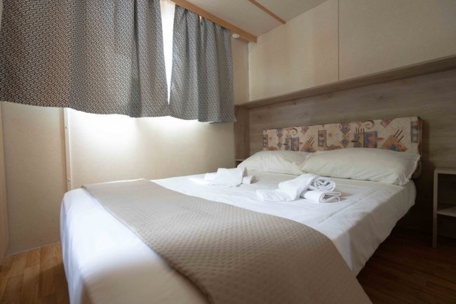 Camera da letto con letto matrimoniale e tende grigie.