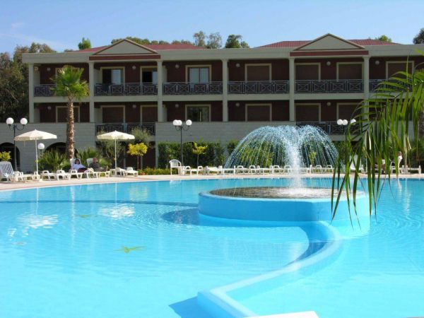 Piscina con fontana centrale, ombrelloni e hotel a più piani sullo sfondo.