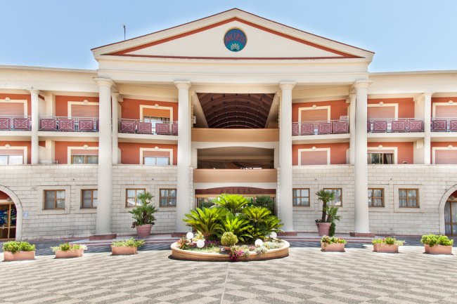 Facciata di un edificio con colonne e balconi, con piante decorative sul davanti.