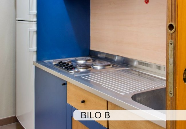 Angolo cottura con piano in acciaio inox, fornelli e frigorifero bianco.