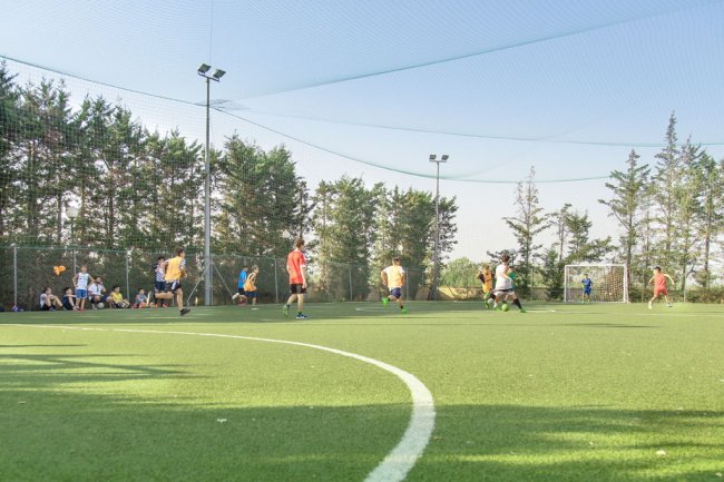 Partita di calcio su un campo all'aperto circondato da alberi.