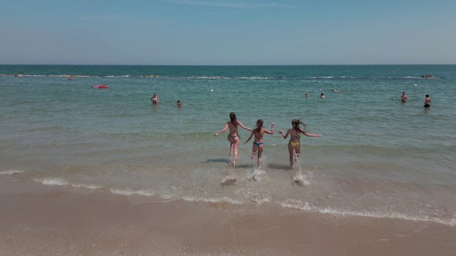 Tre ragazze corrono verso il mare.